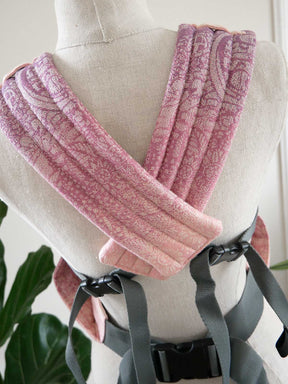 Pink straps of baby carrier on a mannequin with a blurred indoor background