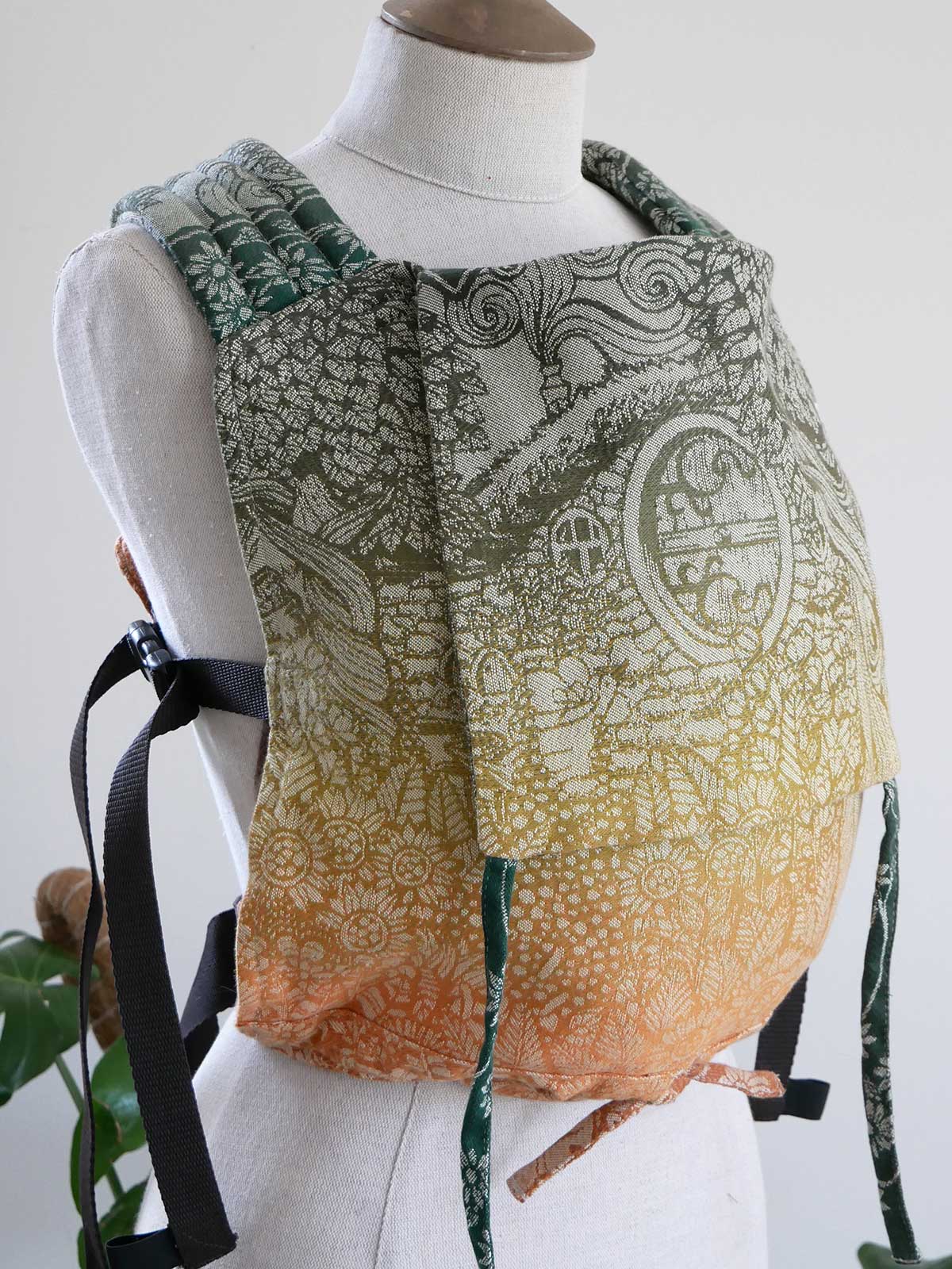 Mannequin wearing a patterned baby carrier with a white background