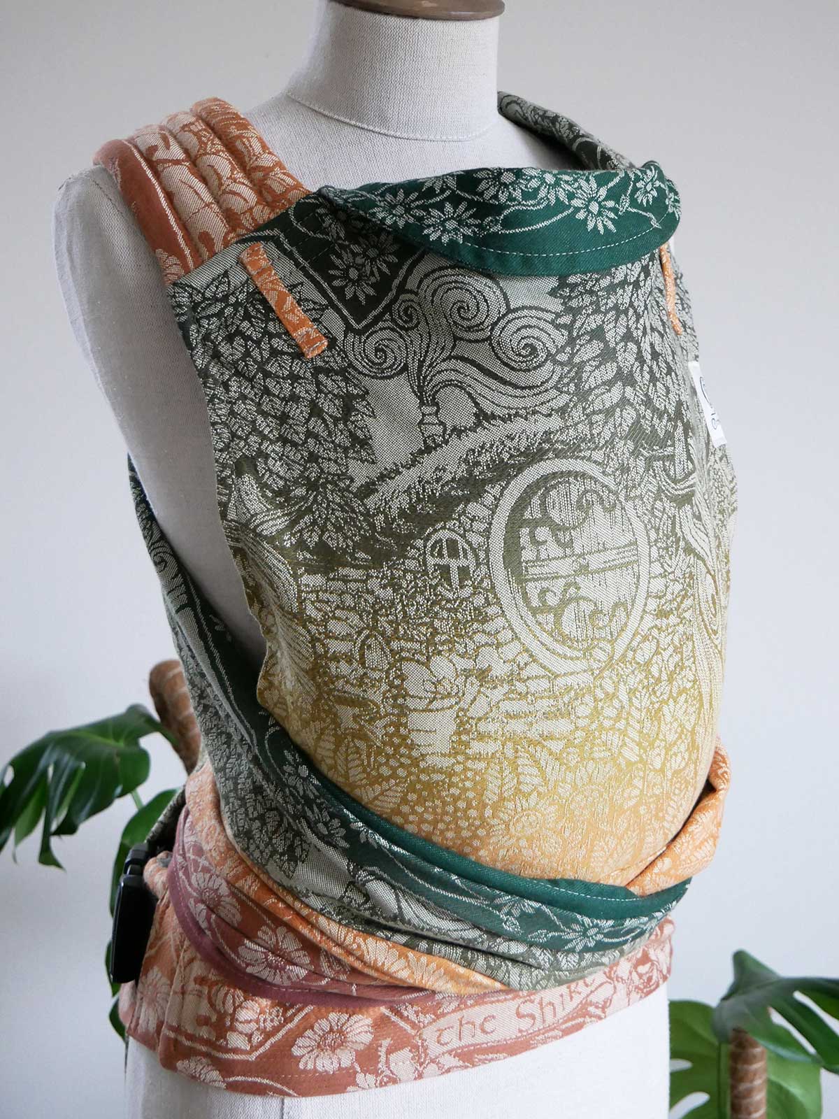 Mannequin wearing Shire Harvest Light Cairis Baby Carrier with autumnal accents