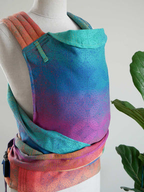 Colorful baby carrier on a mannequin with a plant in the background