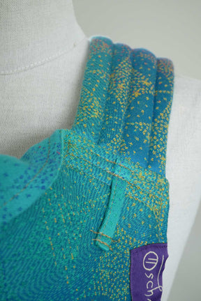 Close-up of a teal and yellow patterned garment with a visible brand logo on a white background