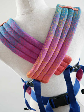 Colorful baby carrier wrap on a mannequin with blue straps.