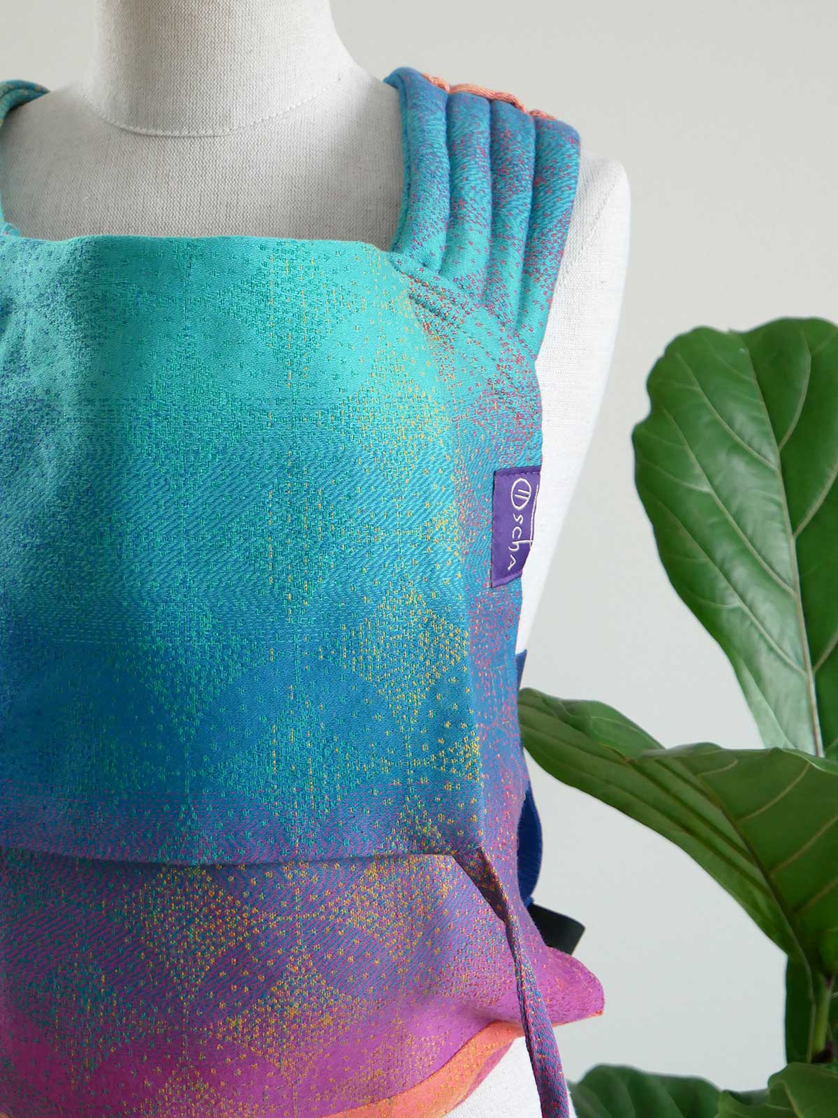 Mannequin wearing a colorful dress with a plant in the background