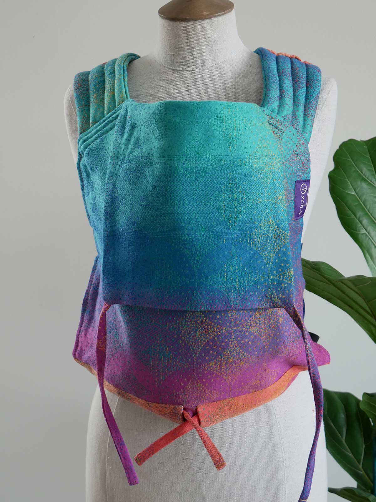 Colorful baby carrier on a mannequin against a neutral background