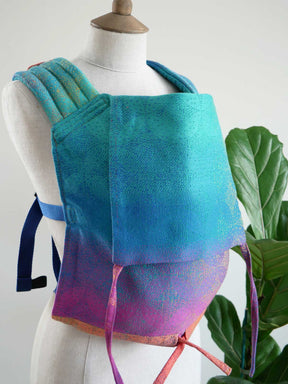 Mannequin wearing a colorful gradient backpack with a plant in the background