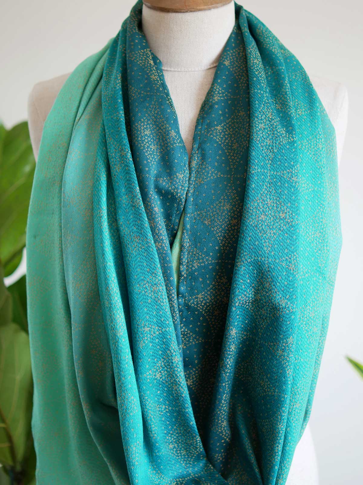 Close up of infinity loop with teal fade and gold details on mannequin
