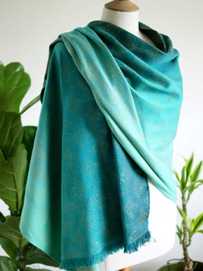 Side view of scarf with teal fade and gold details on mannequin