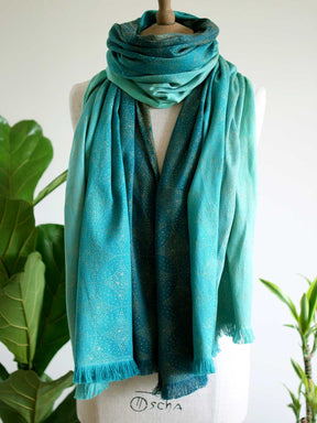 Front view of scarf with teal fade and gold details on mannequin