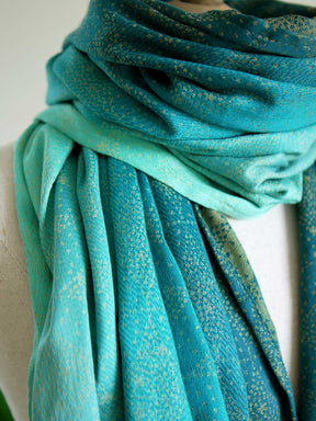 Close up of scarf with teal fade and gold details on mannequin