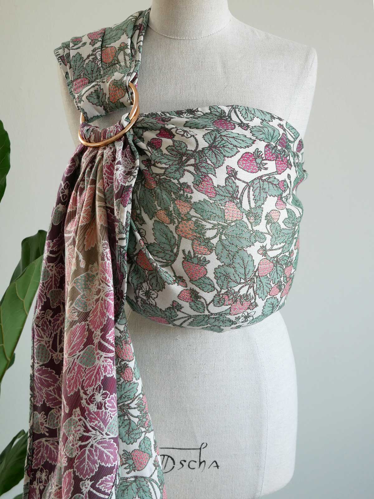 Strawberry patterned baby carrier on a mannequin.