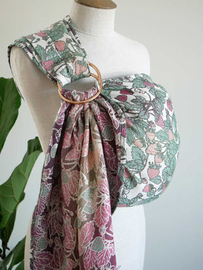 Mannequin wearing a strawberry-patterned ring sling with a green plant in the background