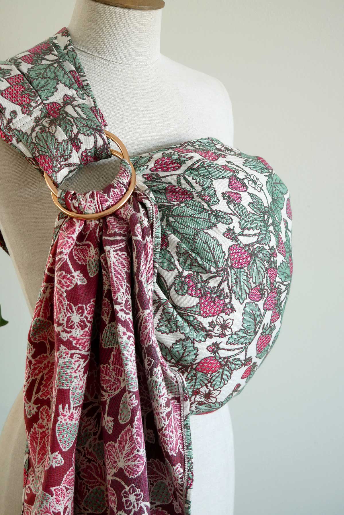 Mannequin wearing a strawberry-patterned ring sling with a gold ring on a white background