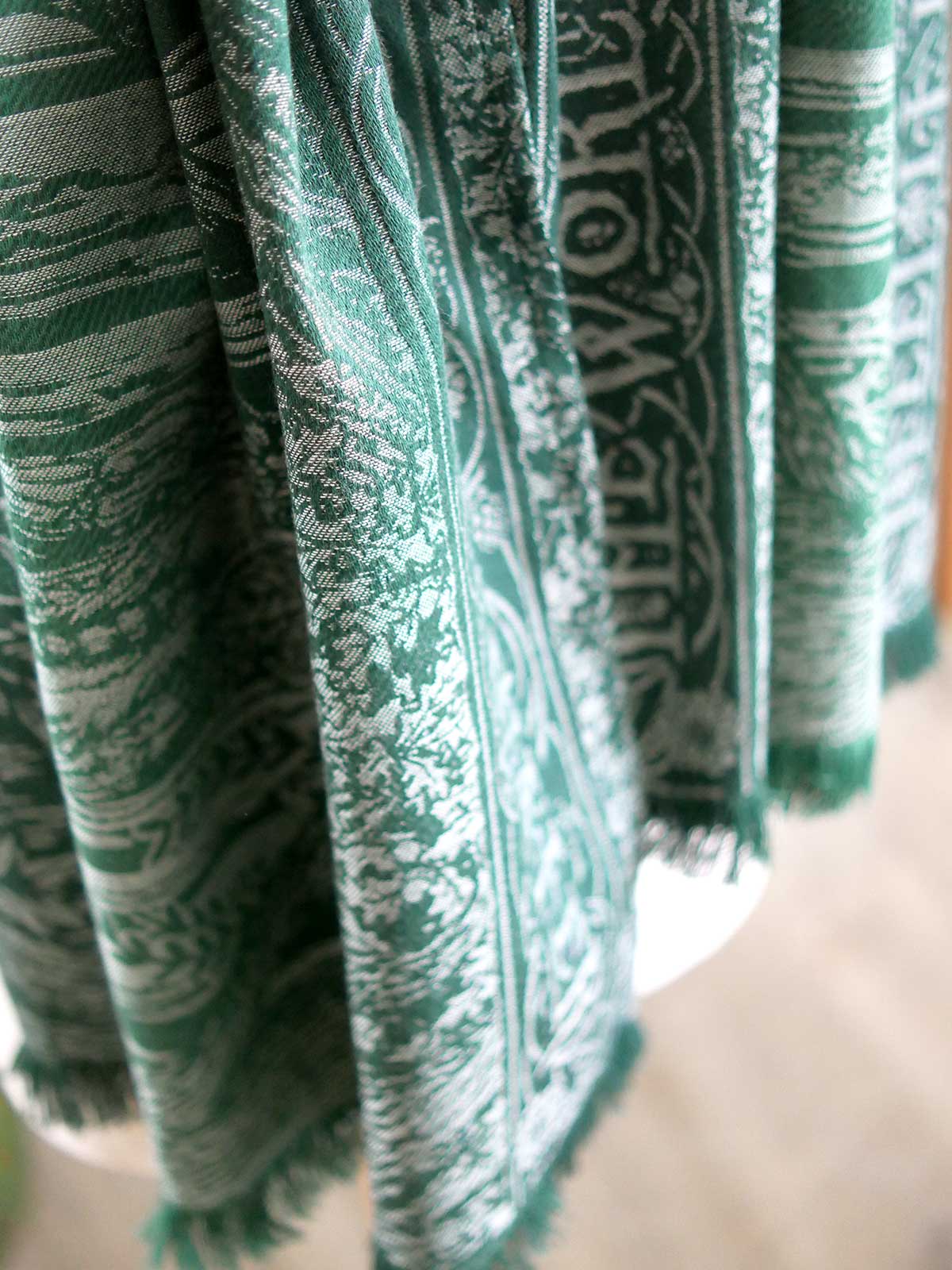 Draped green scarf highlighting fringed edge. 