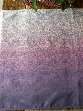 Woven fabric in pinks and purples with a unicorn pattern laid flat on a wooden table