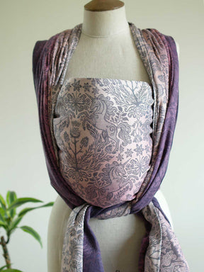 Woven baby wrap in pinks and purples with a unicorn pattern on a mannequin