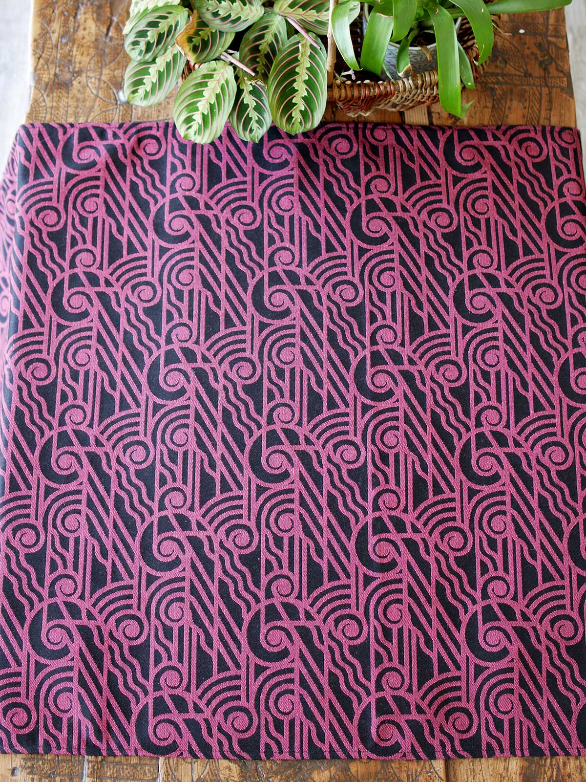 Black wrap with pink art deco pattern on a mannequin laid on a wooden table