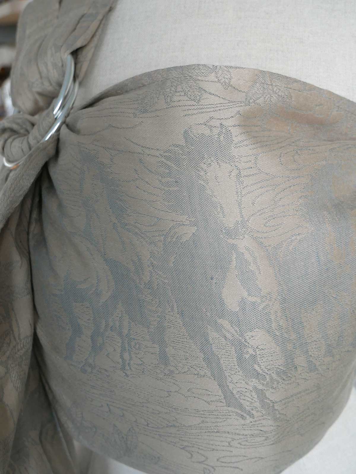 Close-up of a neutral textured ring sling with a horse pattern on a white background