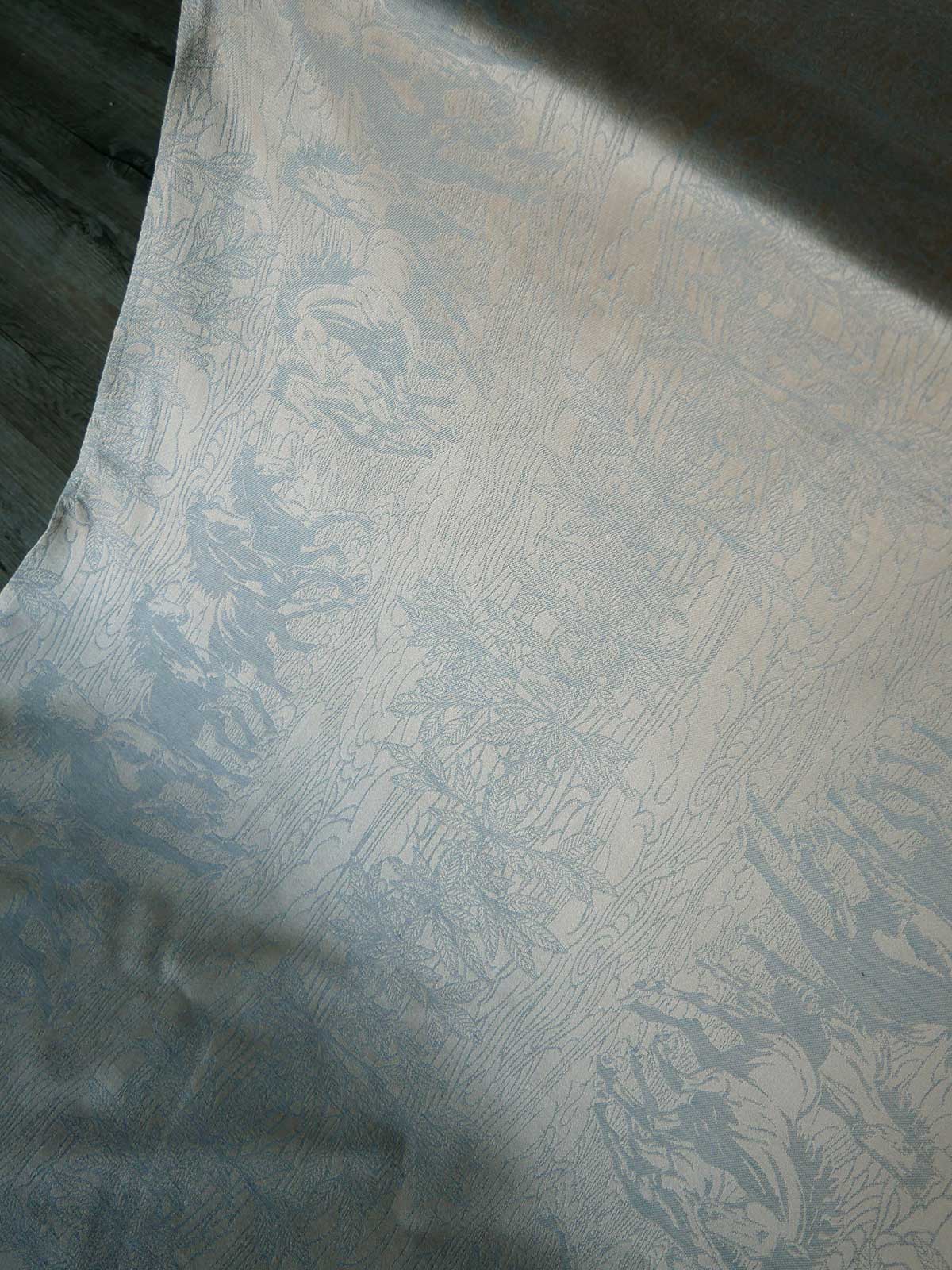 Textured neutral fabric with a subtle horse pattern on a dark background