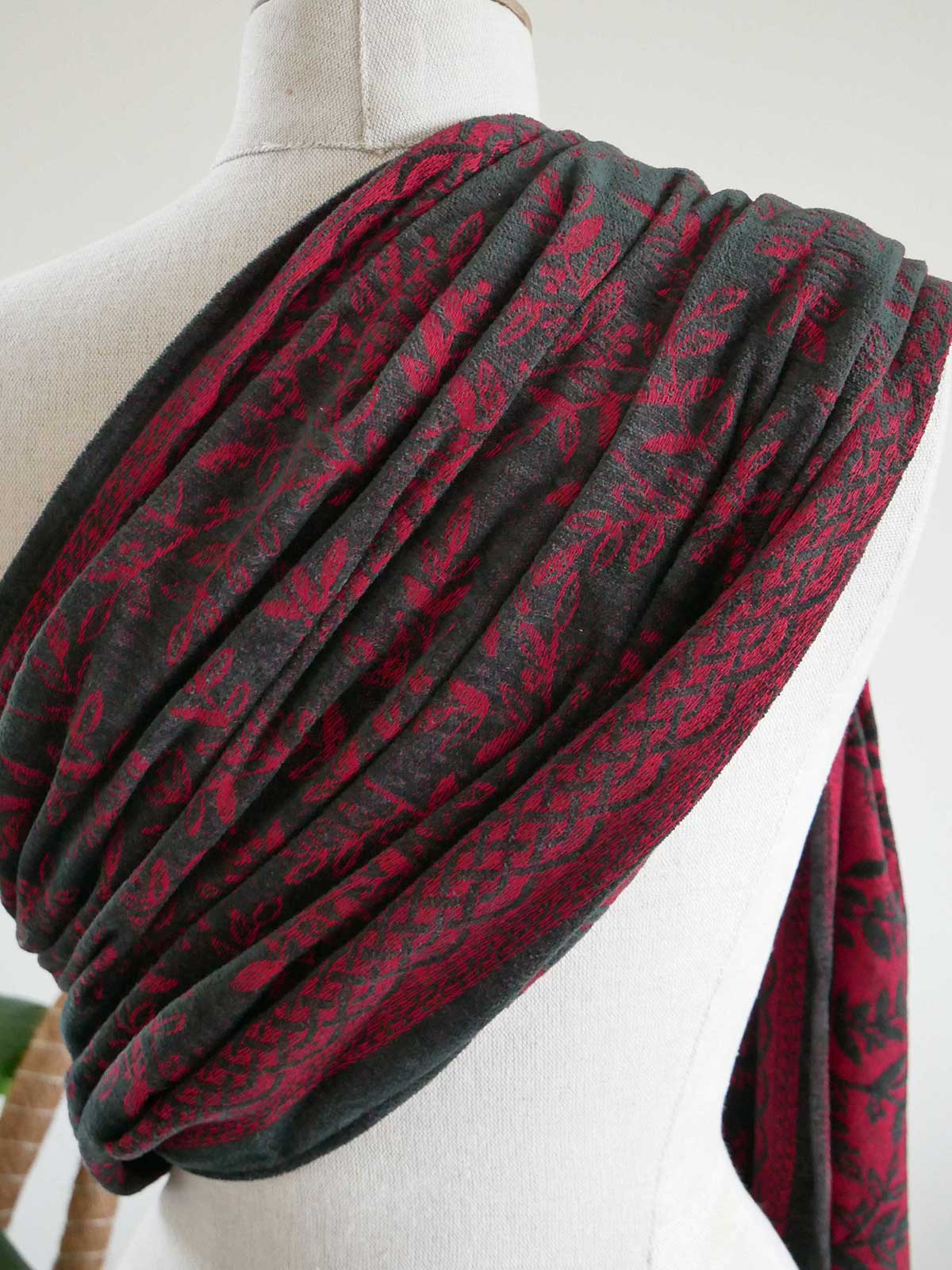 Red and black patterned ring sling on a mannequin against a white background