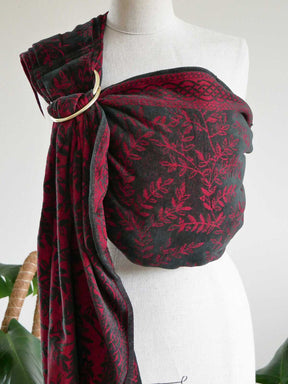 Red and black patterned baby ring sling on a mannequin against a white background