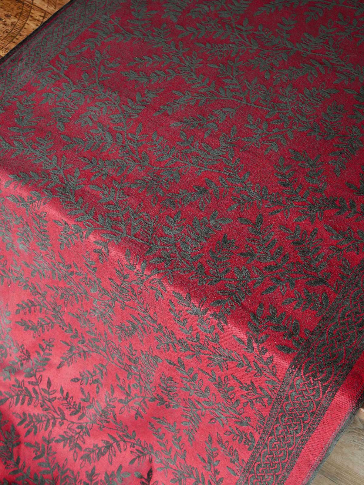Red fabric with black floral pattern on a wooden surface