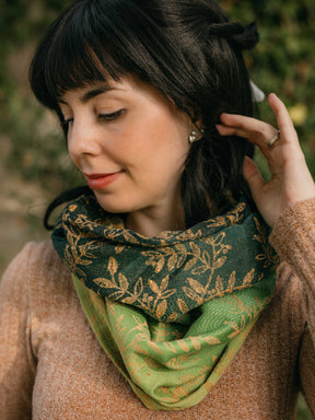 Woman wearing a green shawl round her neck with gold leaf pattern 