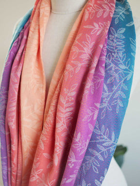 Colorful scarf with leaf pattern draped over a mannequin against a neutral background