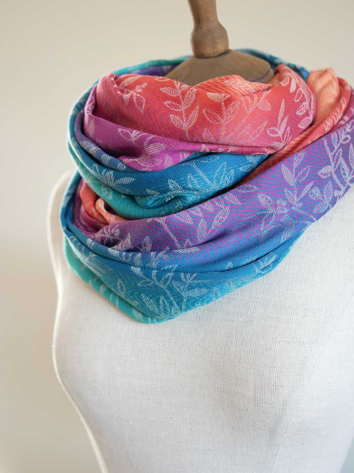 Colorful scarf with floral pattern on a mannequin against a plain background