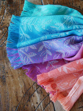Stack of colorful scarves with floral patterns on a wooden surface