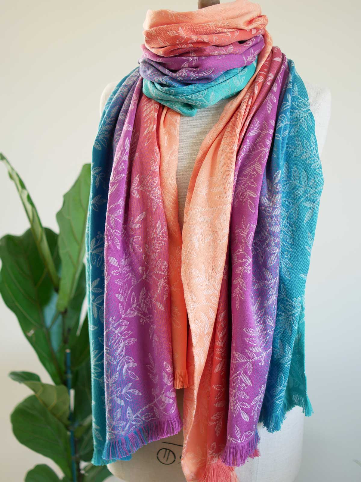 Colorful scarf with floral pattern draped over a mannequin against a white background.