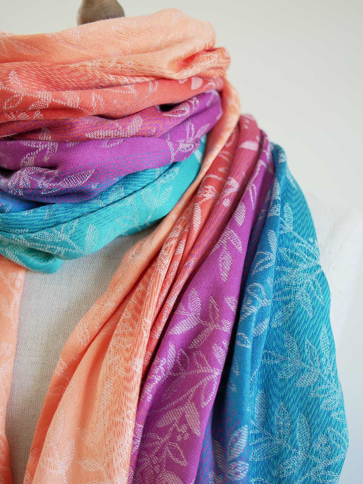 Stack of colorful scarves with floral patterns on a light background