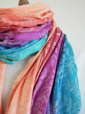 Stack of colorful scarves with floral patterns on a light background