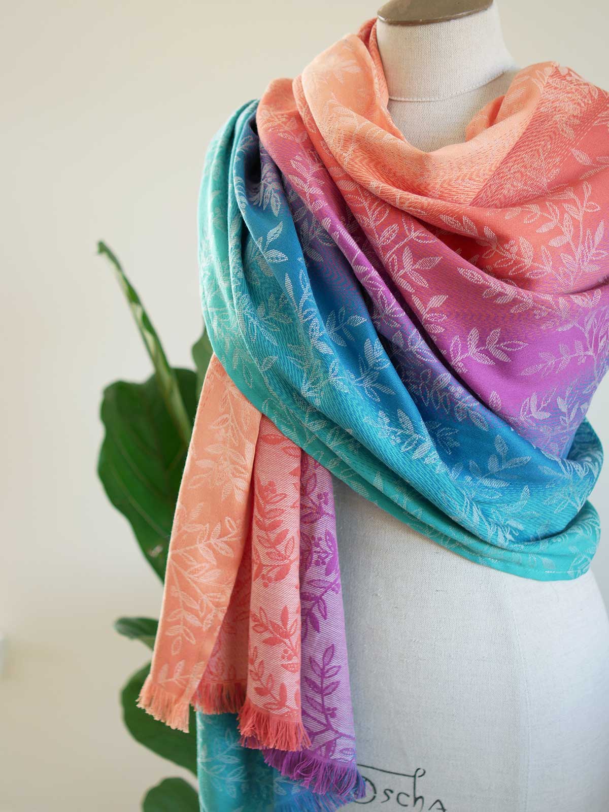 Colorful scarf with floral pattern draped over a mannequin against a white background