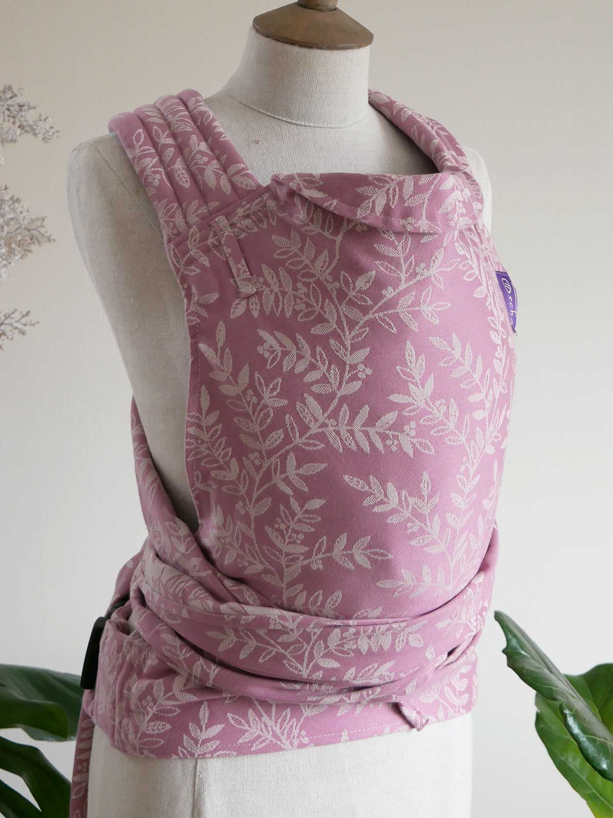 Pink floral baby carrier on a mannequin against a white background