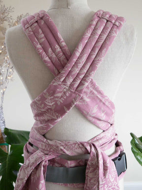 Pink floral-patterned baby carrier on a mannequin against a neutral background