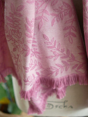 Close up of Pink fabric with a willow leaf pattern and fringes on the end