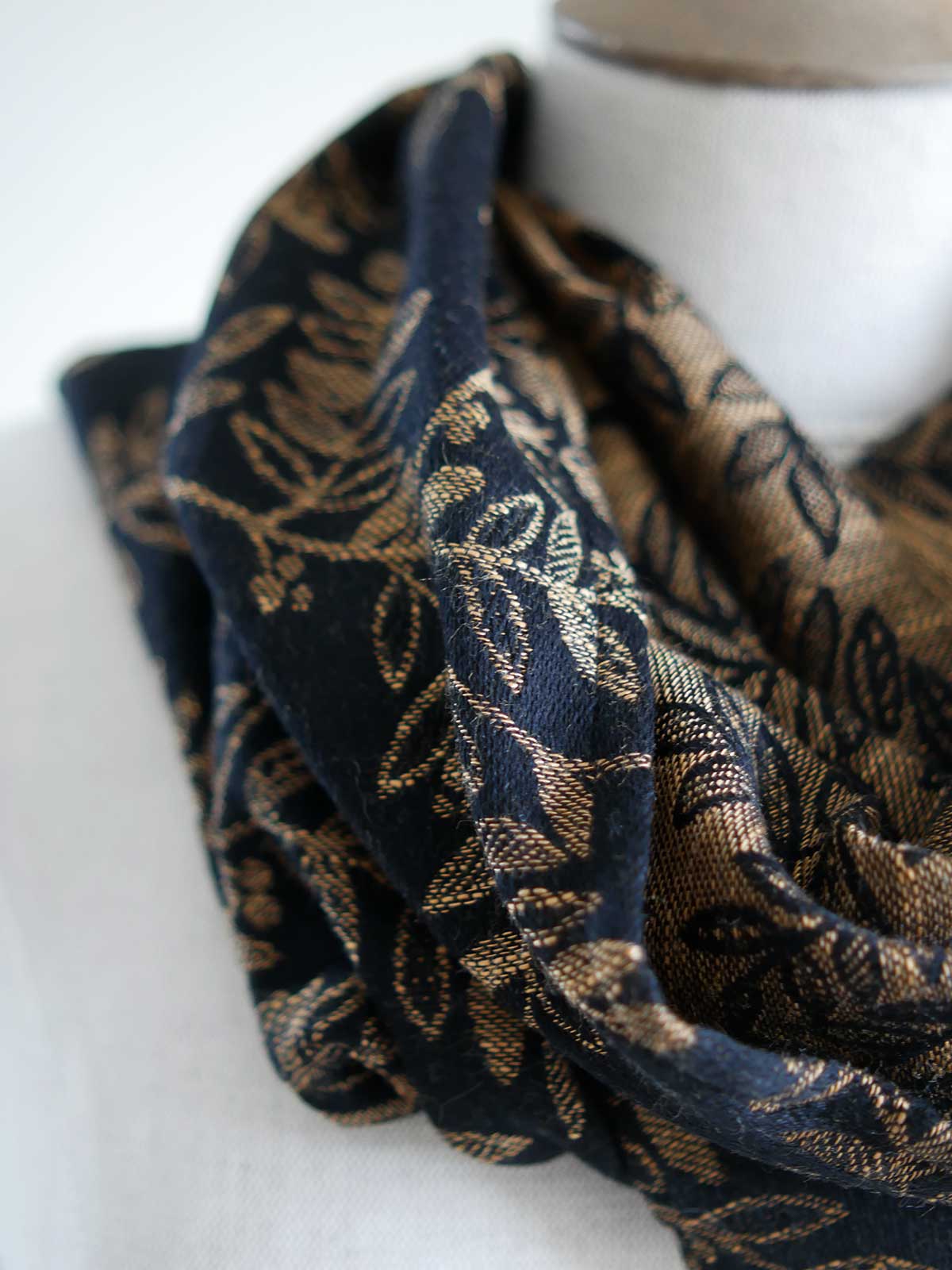 Close up of a black cowl with golden leaves on a mannequin