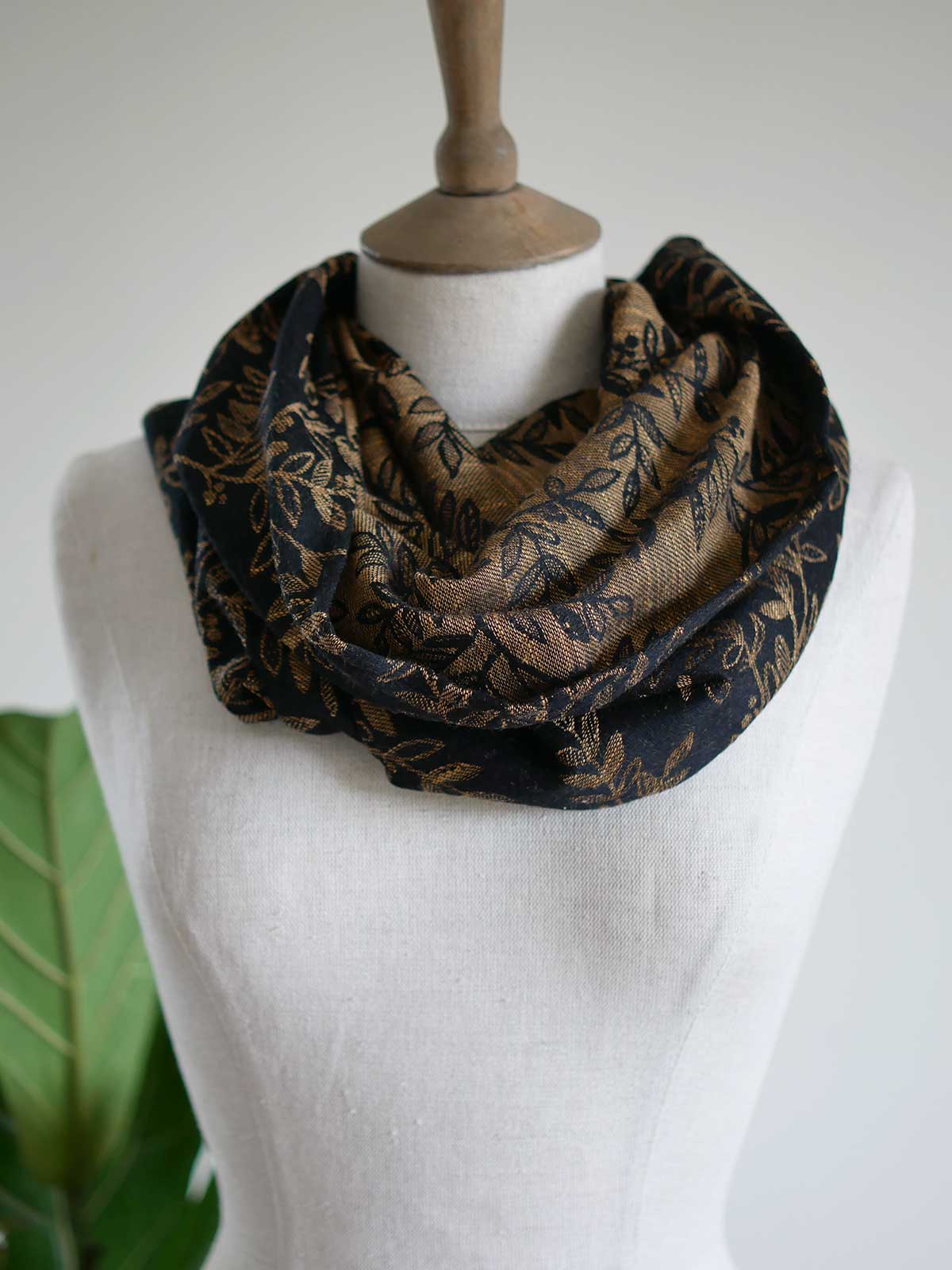 Black cowl with golden leaves draped on a mannequin