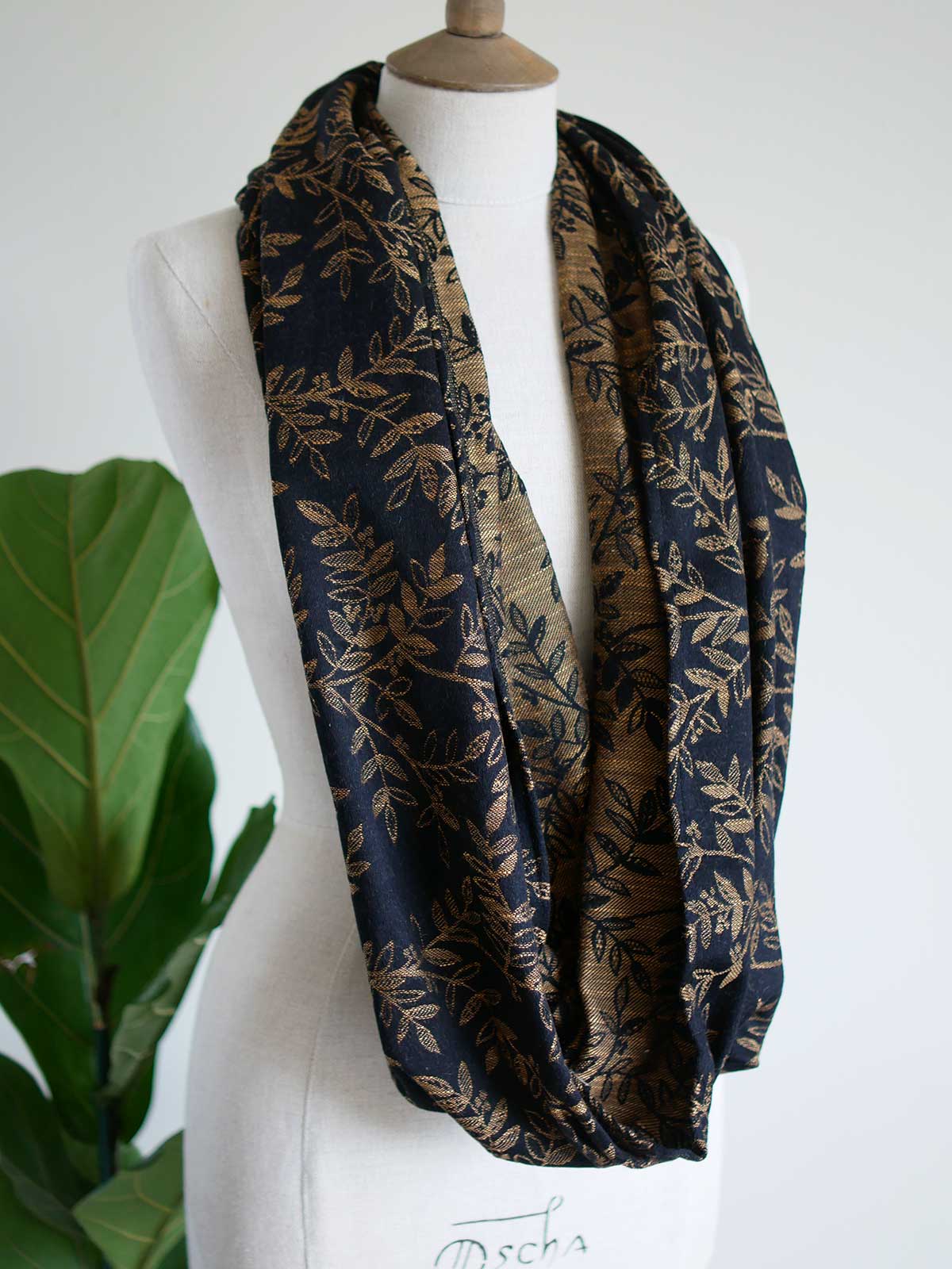 Black infinity loop with golden leaves draped on a mannequin
