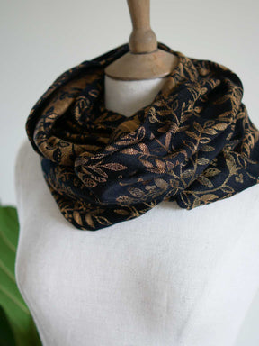 Black infinity loop with golden leaves looped twice on a mannequin