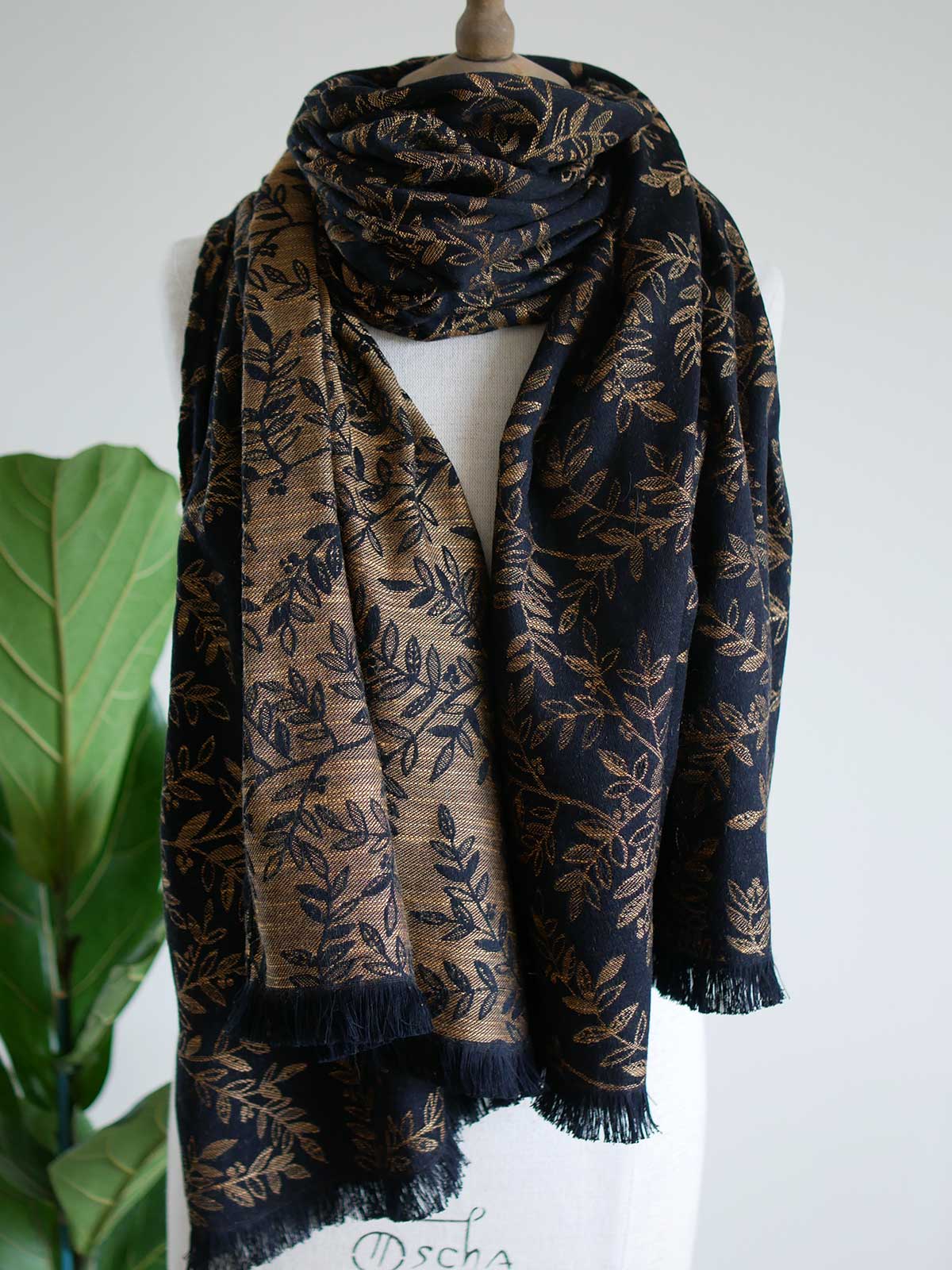 Black scarf with golden leaves draped on a mannequin