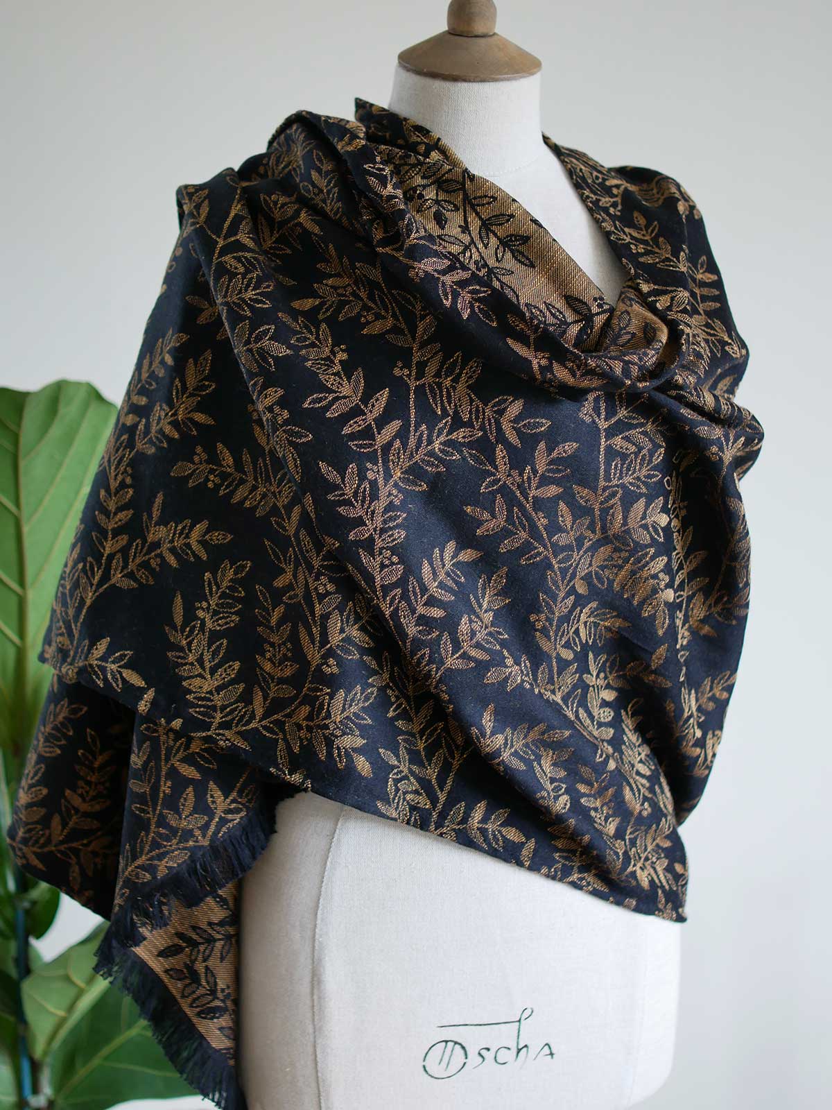 Black scarf with golden leaves draped like a shawl on a mannequin