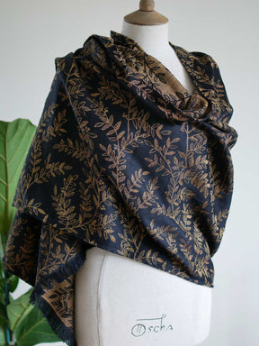 Black scarf with golden leaves draped like a shawl on a mannequin