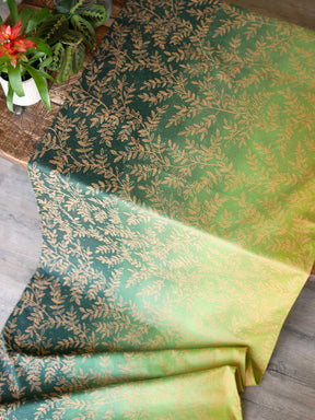 Green fabric with gold leaf pattern laid over a wooden table