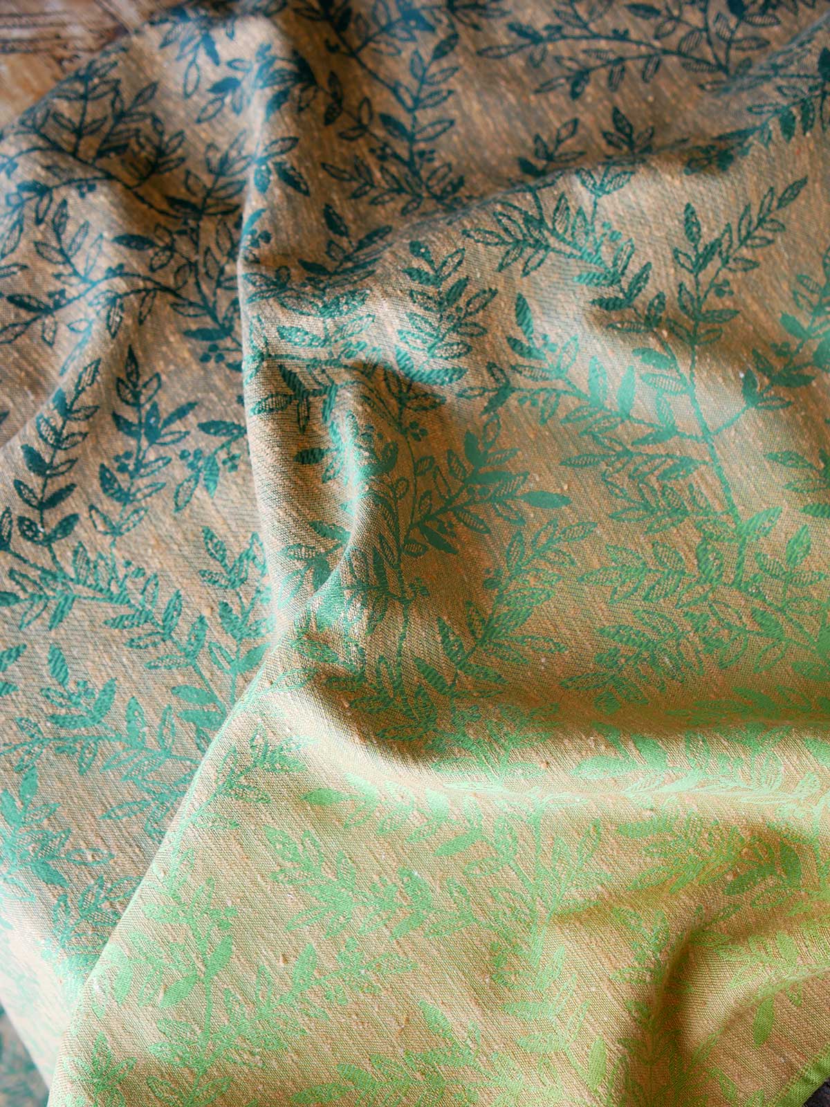 Reverse of a green fabric with gold leaf pattern 
