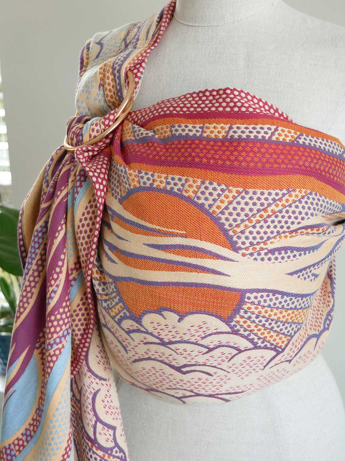 Mannequin wearing a colorful patterned ring sling with a sunset design.