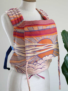Colorful patterned baby carrier on a mannequin with a white background