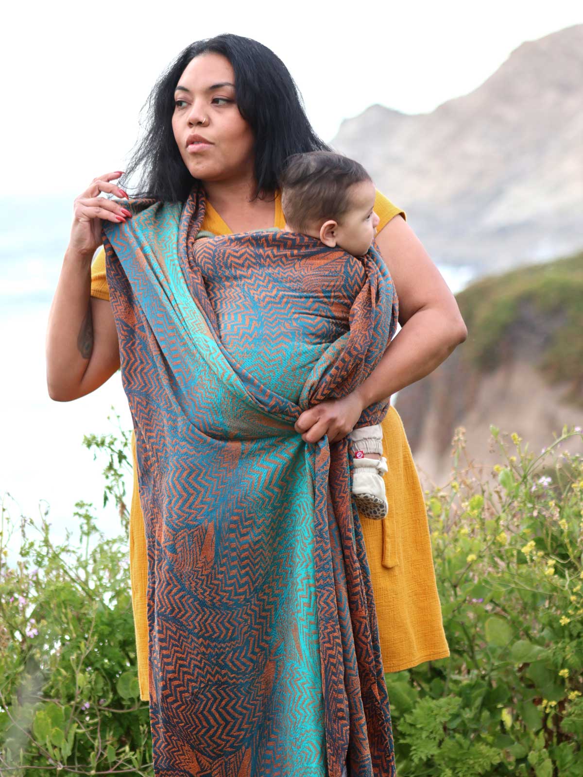 Model wrapping baby with lovely ocean scene behind. 