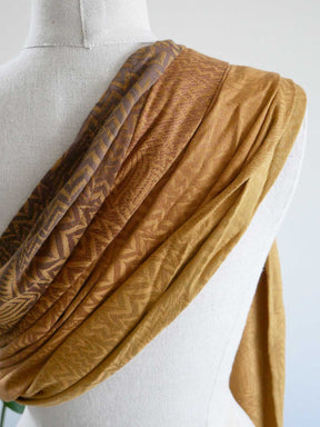 Brown patterned sling draped over a mannequin on a white background