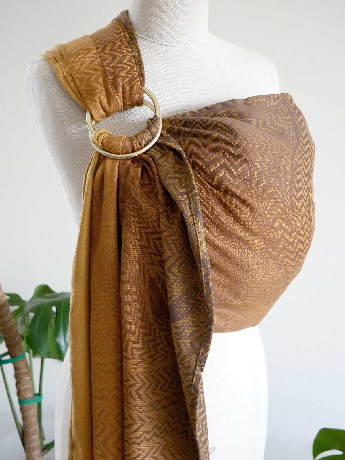 Mannequin wearing a brown patterned ring sling on a white background